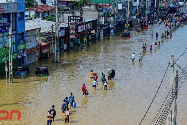 La gente camina por una calle inundada después de fuertes lluvias en Wellampitiya, en las afueras de Colombo. Foto: AFP