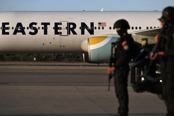 Agentes de policía montan guardia frente a un avión de Eastern Airlines que transportaba migrantes venezolanos repatriados desde Estados Unidos tras aterrizar en el Aeropuerto Internacional Simón Bolívar de Maiquetía, Venezuela, el 3 de diciembre de 2025.(Foto de Juan BARRETO / AFP)
