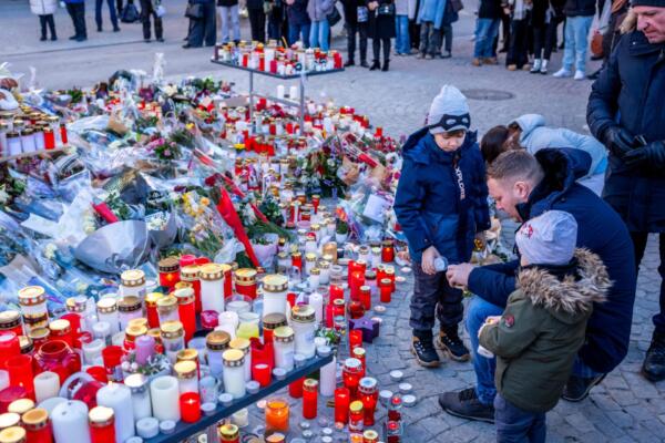 La gente se reúne alrededor de un monumento improvisado para presentar sus respetos colocando flores, velas y mensajes cerca del bar Constellation. Foto: AFP