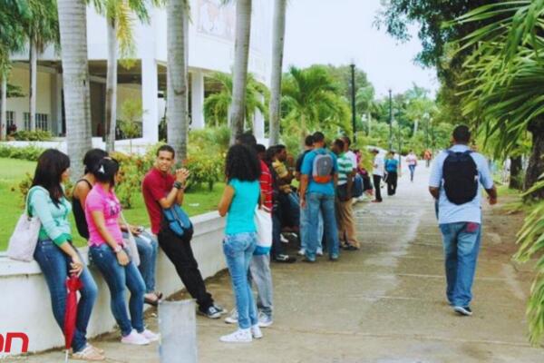 Jóvenes dominicanos reunidos en un espacio público, mientras otros transitan por una vía peatonal. Foto: Fuente externa