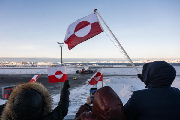 Personas ondean banderas de Groenlandia mientras un avión que transporta a la ministra de Asuntos Exteriores de Groenlandia, Vivian Motzfeldt, se acerca a su posición de estacionamiento en el aeropuerto de Nuuk, Groenlandia, el 20 de enero de 2026. (Foto de Jonathan NACKSTRAND / AFP)
