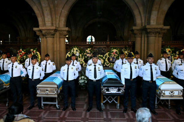 Policías junto a los ataúdes de los policías asesinados durante un funeral en la sede del Ministerio del Interior en la Ciudad de Guatemala el 19 de julio de 2026.  (Foto de JOHAN ORDONEZ / AFP)