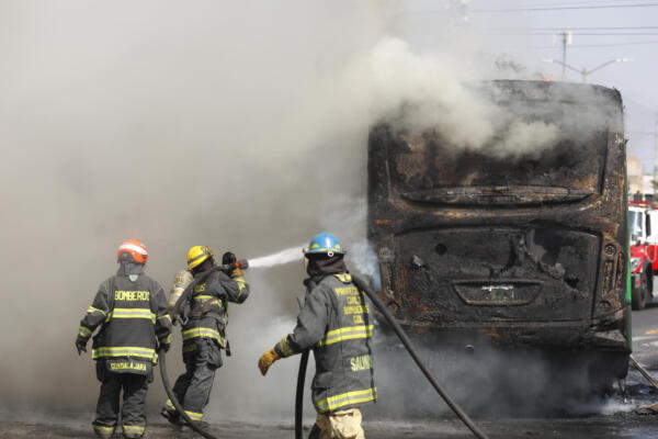 Integrantes del Cuerpo de Bomberos de Guadalajara intentan apagar un vehículo incendiado este domingo, en Guadalajara (México). EFE/ Francisco Guasco