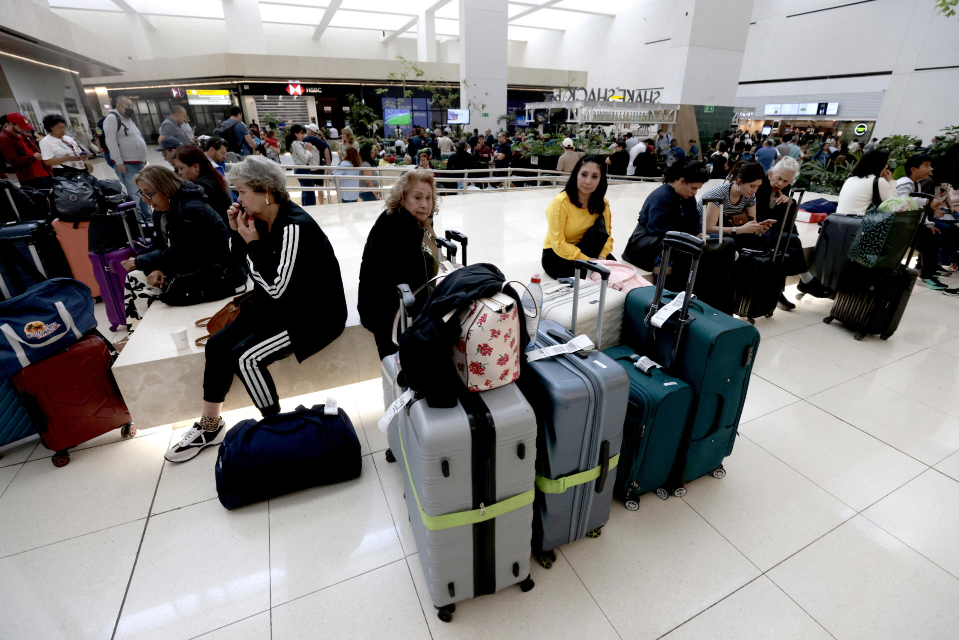 Pasajeros permanecen varados en el Aeropuerto Internacional de Guadalajara tras la suspensión de vuelos y la falta de transporte en Tlajomulco, Jalisco, México, el 22 de febrero de 2026. (Foto de Ulises Ruiz / AFP)