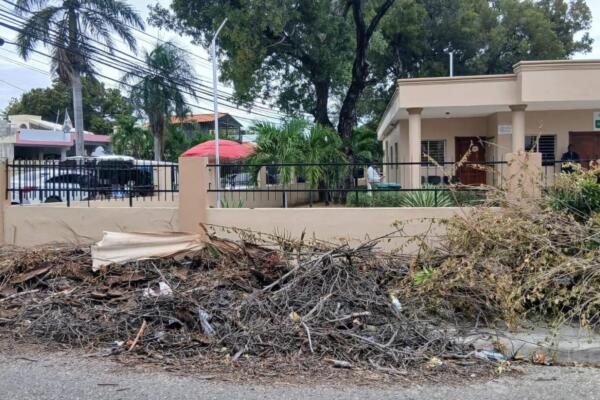 Basura y restos de poda se acumulan junto a una de las paredes del Tribunal de Niños, Niñas y Adolescentes de Barahona, en la calle Colón, provocando malestar entre ciudadanos y visitantes.