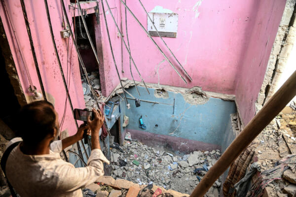 Un camarógrafo graba imágenes en el lugar del derrumbe de un edificio tras una explosión en Karachi el 19 de febrero de 2026. El derrumbe de un edificio causado por una explosión en Karachi, una megaciudad del sur de Pakistán, causó la muerte de al menos 16 personas el 19 de febrero, incluidos niños, según informaron las autoridades. (Foto de Rizwan TABASSUM / AFP)
