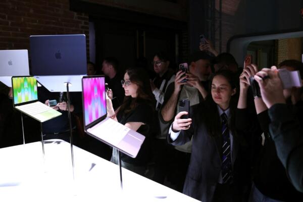 Personas toman fotos de algunas de las nuevas computadoras Apple durante el evento de lanzamiento 