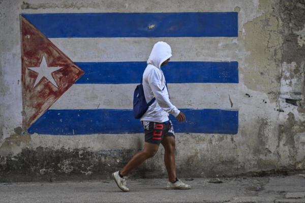 Un hombre pasa junto a un muro pintado con la bandera cubana en una calle de La Habana durante un apagón nacional.