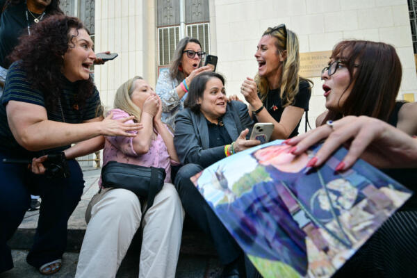 Laura Marquez-Garrett (C), plaintiffs' attorney for SMVLC (Social Media Victims Law Center), gathers with family members of victims as they react to news that the jury has found Meta and YouTube liable in the social media addiction trial, outside the Los Angeles Superior Court , in Los Angeles, on March 25, 2026. A Los Angeles jury on Wednesday found Meta and YouTube liable for harming a young woman through the addictive design of their social media platforms and ordered the companies to pay $3 million in damages. The decision delivering a landmark verdict that could reshape how the tech industry faces legal accountability for the mental health of young users. (Photo by Frederic J. Brown / AFP)