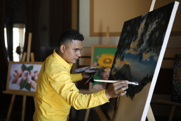 Un privado de la libertad pinta en la inauguración de una exposición este martes, en San Salvador (El Salvador). EFE/ Rodrigo Sura