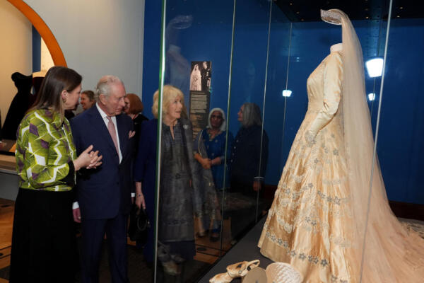El rey Carlos III y la reina Camila de Gran Bretaña escuchan a Caroline de Guitautv, curadora de la exposición y supervisora ​​de las Obras de Arte del Rey, mientras contemplan las piezas expuestas, incluyendo atuendos usados ​​por su difunta madre, la reina Isabel II, en la nueva exposición del Royal Collection Trust: «La reina Isabel II: Su vida con estilo», que se inaugura en la Galería del Rey en el Palacio de Buckingham, Londres, el 20 de abril de 2026.  (Foto de Aaron Chown / POOL / AFP)
