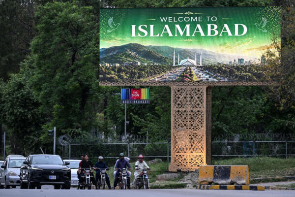 Commuters wait at a traffic signal beside a digital screen in Islamabad on April 24, 2026. Iran's state media confirmed that Foreign Minister Abbas Araghchi would travel on April 24 to Pakistan, which has been mediating between the Islamic Republic and the United States in a bid to end the Middle East war. (Photo by Farooq NAEEM / AFP)