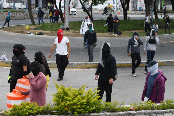 Encapuchados caminan durante una manifestación este martes, afuera de la Universidad de San Carlos de Guatemala en Ciudad de Guatemala (Guatemala). EFE/ Alex Cruz