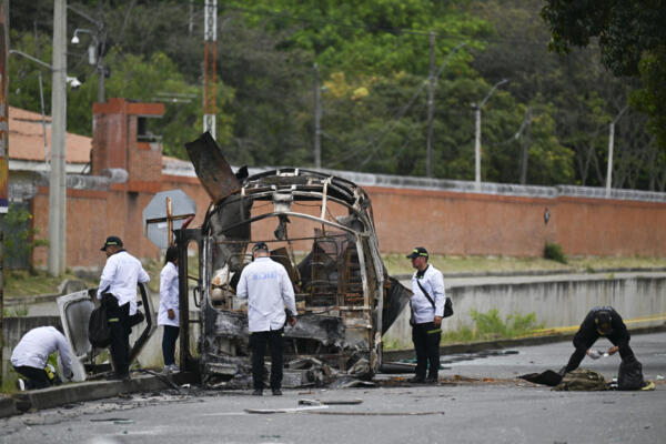 Agentes de la Sección de Investigación Criminal de la Policía de Colombia (Sijin) inspeccionan un autobús incendiado tras la explosión de una bomba cerca de una base militar en Cali, departamento del Valle del Cauca, Colombia, el 24 de abril de 2026. (Foto de JOAQUIN SARMIENTO / AFP)