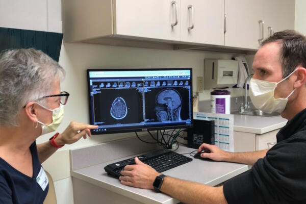 Un ensayo clínico liderado por la Facultad de Medicina de la Universidad de Washington (WashU Medicine) y llevado a cabo en el Siteman Cancer Center ha descubierto que una vacuna personalizada para tratar el glioblastoma es segura y podría mejorar potencialmente los resultados. Una de las participantes del ensayo, a la izquierda, revisa un escáner con el investigador principal del estudio, Tanner Johanns, oncólogo de WashU Medicine. Fotografía facilitada por Scott Garland.
