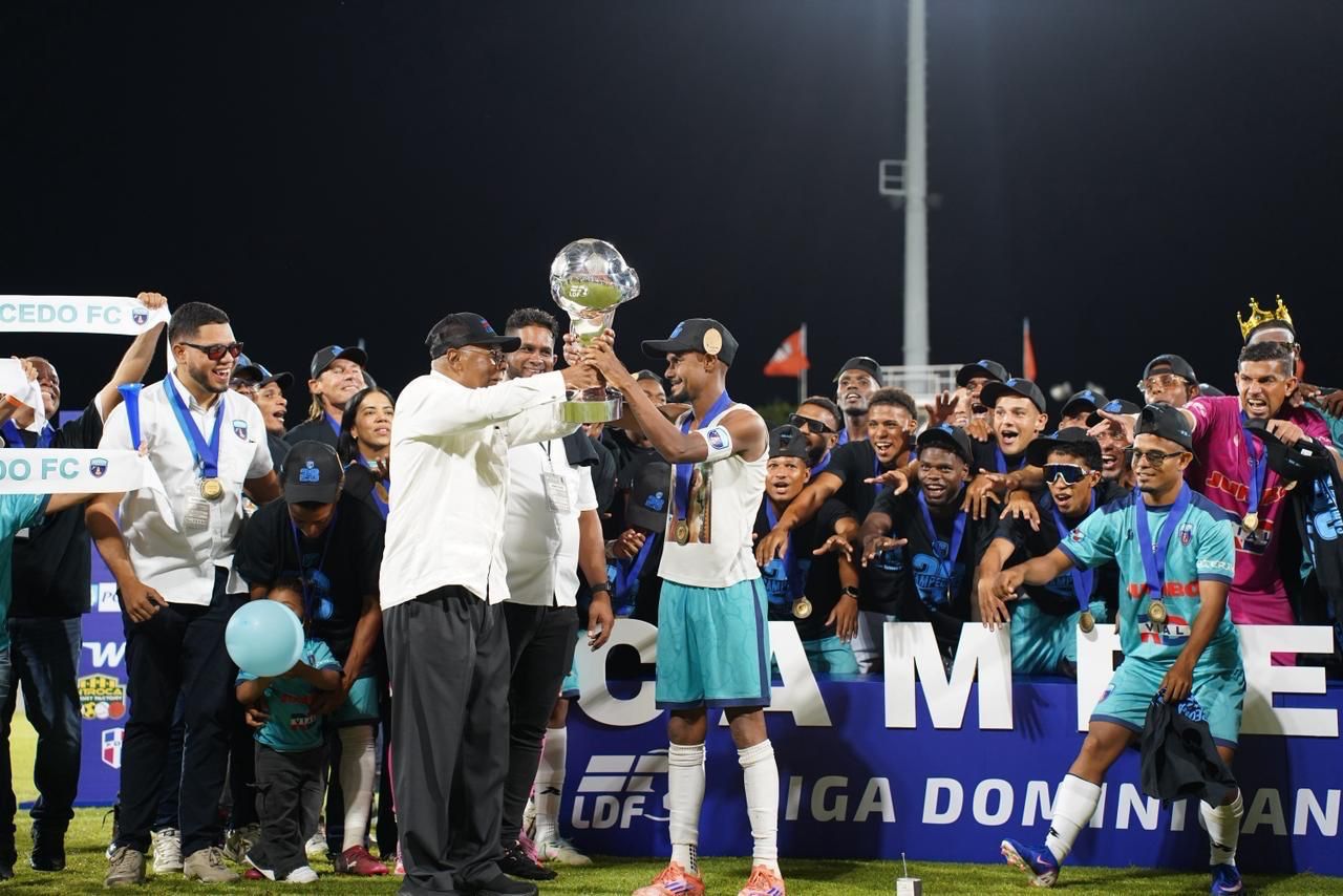 Milton Ray Guevara, presidente de la LDF, entrega el trofeo de campeón al capitán de Salcedo FC, Carlos Rossell.
