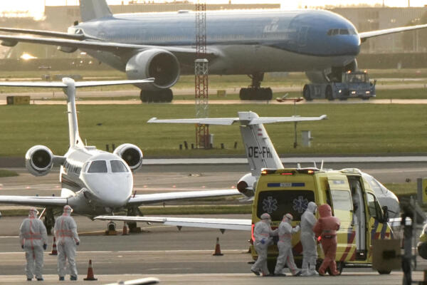 Una persona con un traje de protección (2R) es escoltada a una ambulancia desde un avión medicalizado que supuestamente transportaba a algunos de los pasajeros del crucero MV Hondius, presuntamente infectado con hantavirus, en el aeropuerto de Schiphol, cerca de Ámsterdam, el 6 de mayo de 2026.  (Foto de Lina Selg / AFP)
