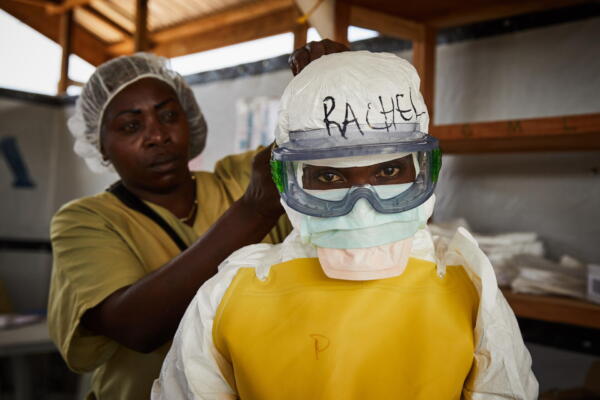 Un par de trabajadoras de la salud fueron captadas el pasado 12 de mayo al ataviarse con equipos de protección personal, antes entrar en una zona de tratamiento de alto riesgo de propagación del virus del ébola, en un centro de salud en Beni, Kivu del Norte, República Democrática del Congo. EFE/Hugh Kinsella