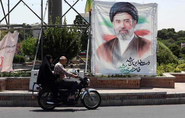 Dos personas en motocicleta cerca de una fotografía del líder supremo de Irán, Mojtaba Khamenei, en una calle de Teherán.
Foto: Fuente externa 