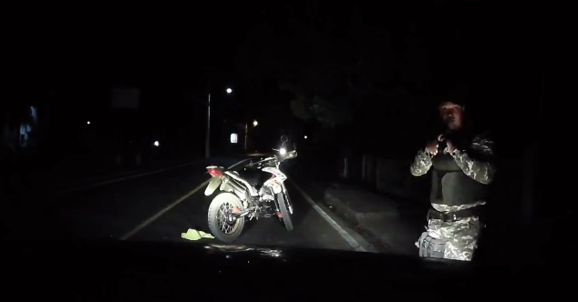 Policía a punta a un civil que está estacionado con las gomas del vehículo pinchado