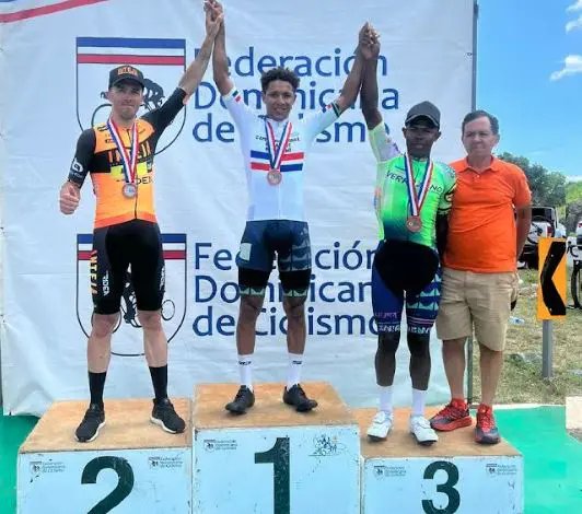 El santiaguero Pablo Alcides Reyes (Team Verrazano) ocupó el escalón más alto del podio del campeonato nacional de ruta élite. Figuran a su lado, Diego Milán Jiménez, segundo, y su compañero de equipo Ruddy Germoso. A la derecha, Rafael Tejada Martínez, secretario de la Federación Dominicana de Ciclismo. (Foto Fuente Externa)