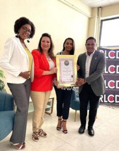 Lissette Selman recibe un reconocimiento de la mano de Jerfferson Rodríguez presidente de RLCD