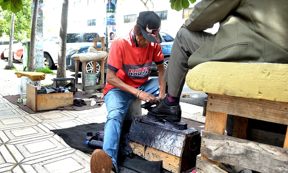 Laitiedo Cordero limpia zapatos en la calle Hipólito Heredia en el sector La Feria.