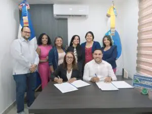 Erminda Decena y Victor Torres firman el convenio. Miembros de las juntas directivas de las entidades les acompañan.