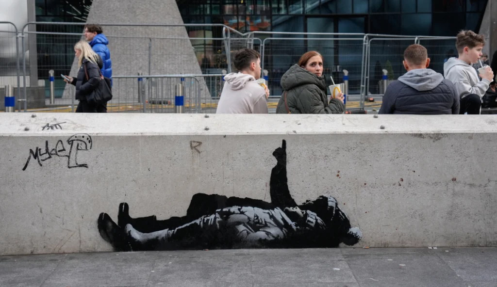 Peatones pasan junto a un mural en el lateral de una pared, supuestamente creado por el artista callejero Banksy, según los medios locales, en la zona de Tottenham Court Road, en el centro de Londres, el 22 de diciembre de 2025. (Foto de CARLOS JASSO / AFP)