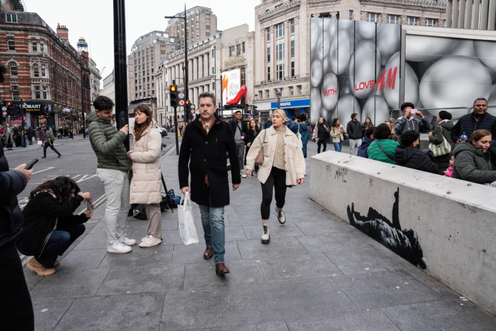 Peatones pasan junto a un mural en el lateral de una pared, supuestamente creado por el artista callejero Banksy, según los medios locales, en la zona de Tottenham Court Road, en el centro de Londres, el 22 de diciembre de 2025. (Foto de CARLOS JASSO / AFP)