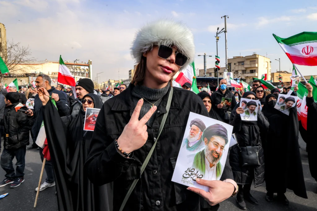 Una mujer posa con una fotografía del nuevo líder supremo de Irán, el ayatolá Mojtaba Khamenei (derecha), junto a su difunto padre, Ali Khamenei, durante una manifestación en su apoyo en la plaza Enghelab, en el centro de Teherán