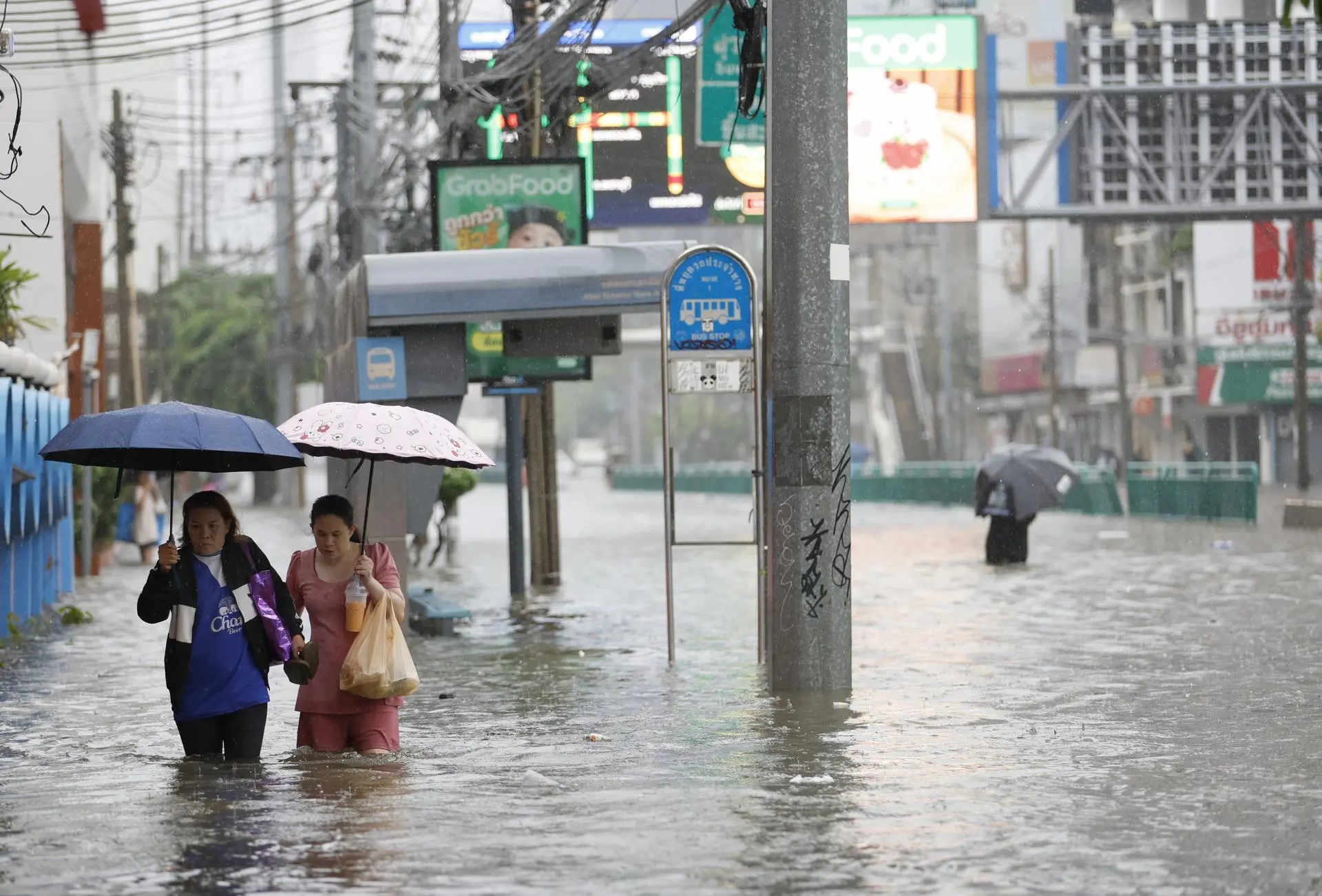 Residentes caminan entre el agua durante un aguacero en la calle Phetchaburi de Bangkok, cuyos 50 distritos han sido declarados zona de desastre por inundaciones tras las persistentes y fuertes lluvias provocadas por un intenso sistema de baja presión, sumado a los patrones estacionales del monzón